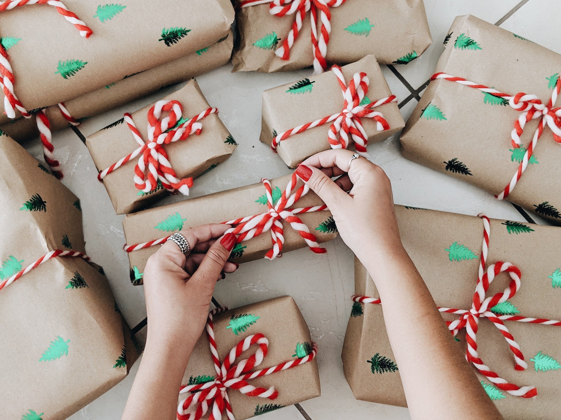 person wrapping presents with red and white ribbon.