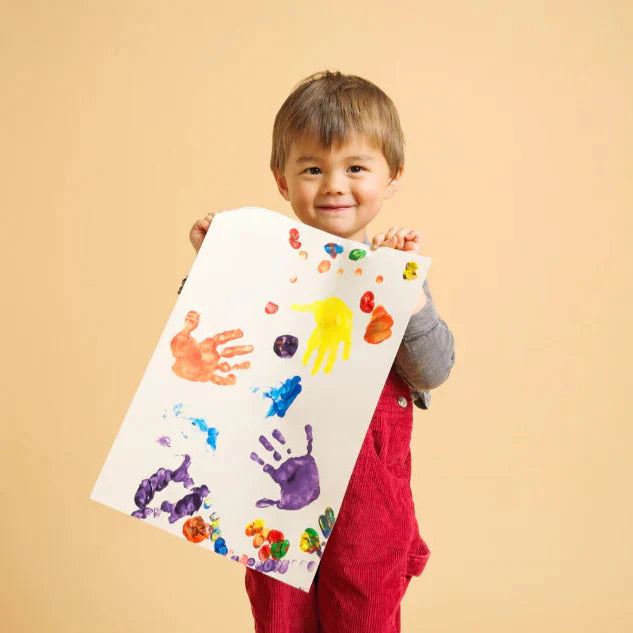 Child in a pink shirt with red paint on hands and paper