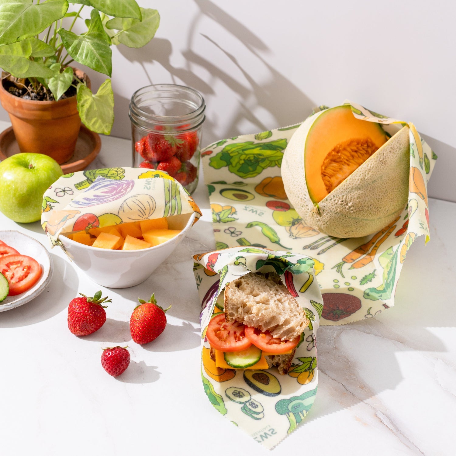 Reusable food wraps with fruits and vegetables on a white surface