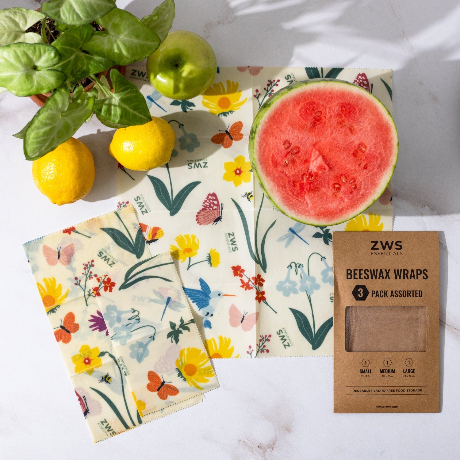 ZWS beeswax wraps with a half-cut watermelon and lemons on a white surface
