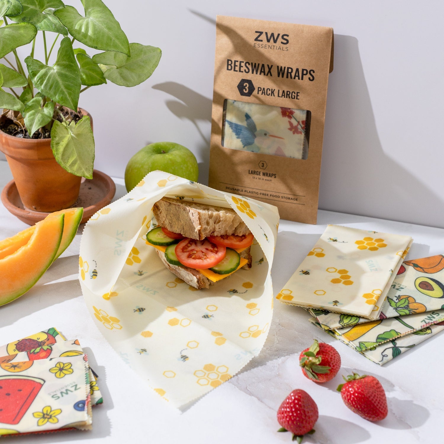 Beeswax wraps with a sandwich and fruits on a table, featuring ZWS packaging.