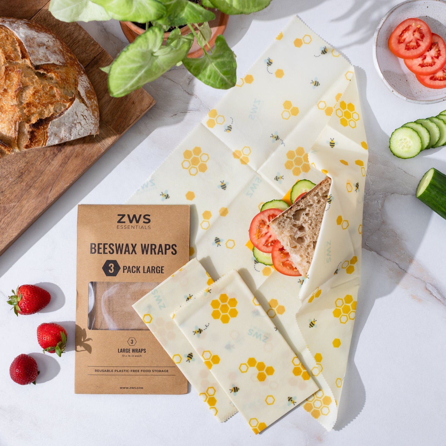 Beeswax wraps with a sandwich and vegetables on a white surface, next to a package of ZWS Beeswax Wraps.