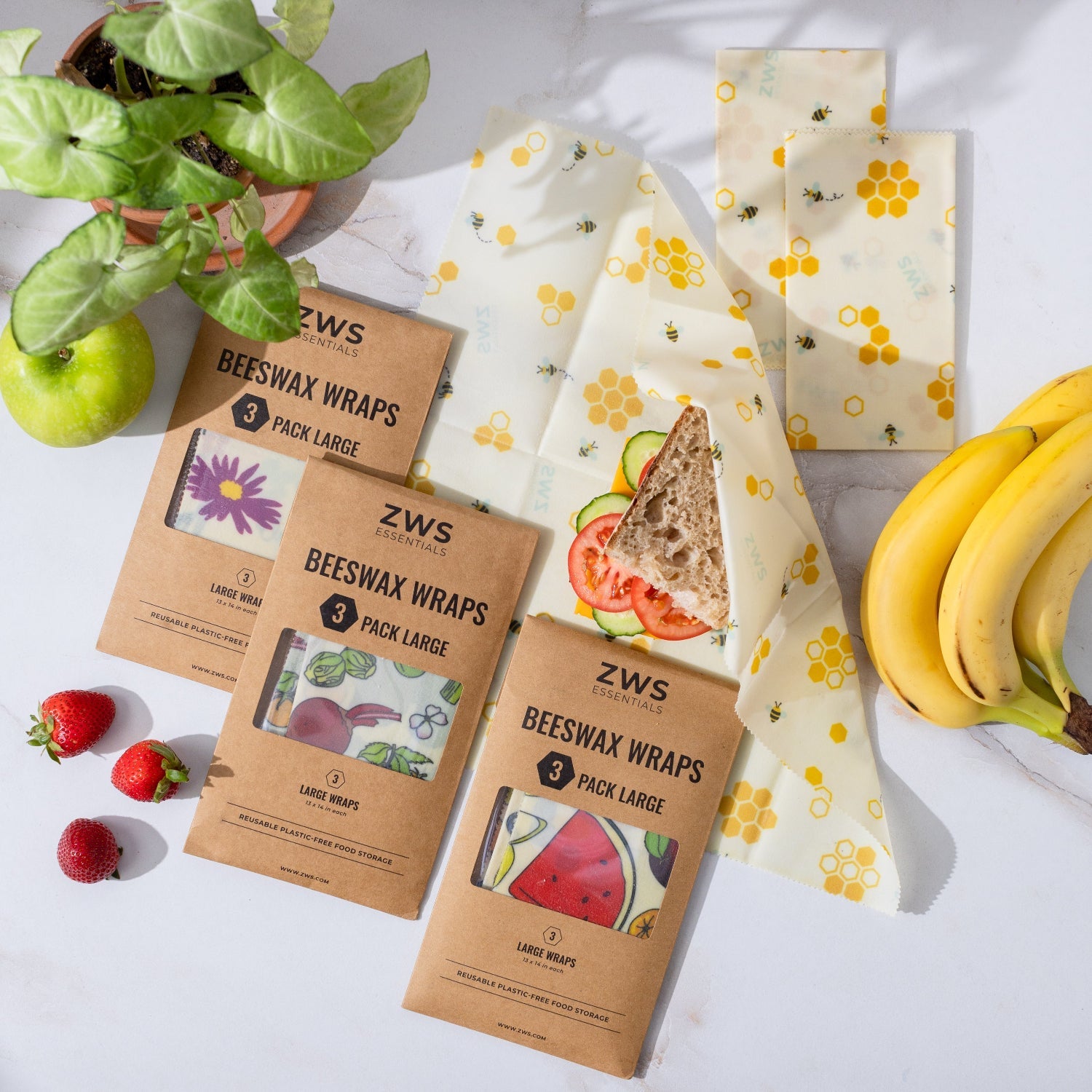 ZWS beeswax wraps with packaging on a light surface with fruits and a plant.
