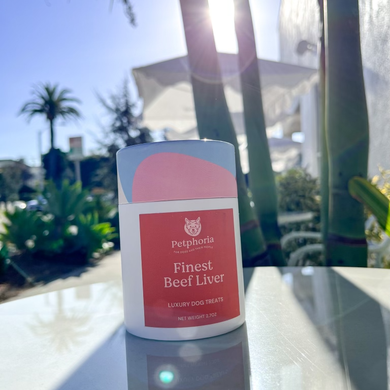 Petfood container labeled 'Finest Beef Liver' on a reflective surface with a blurred outdoor background