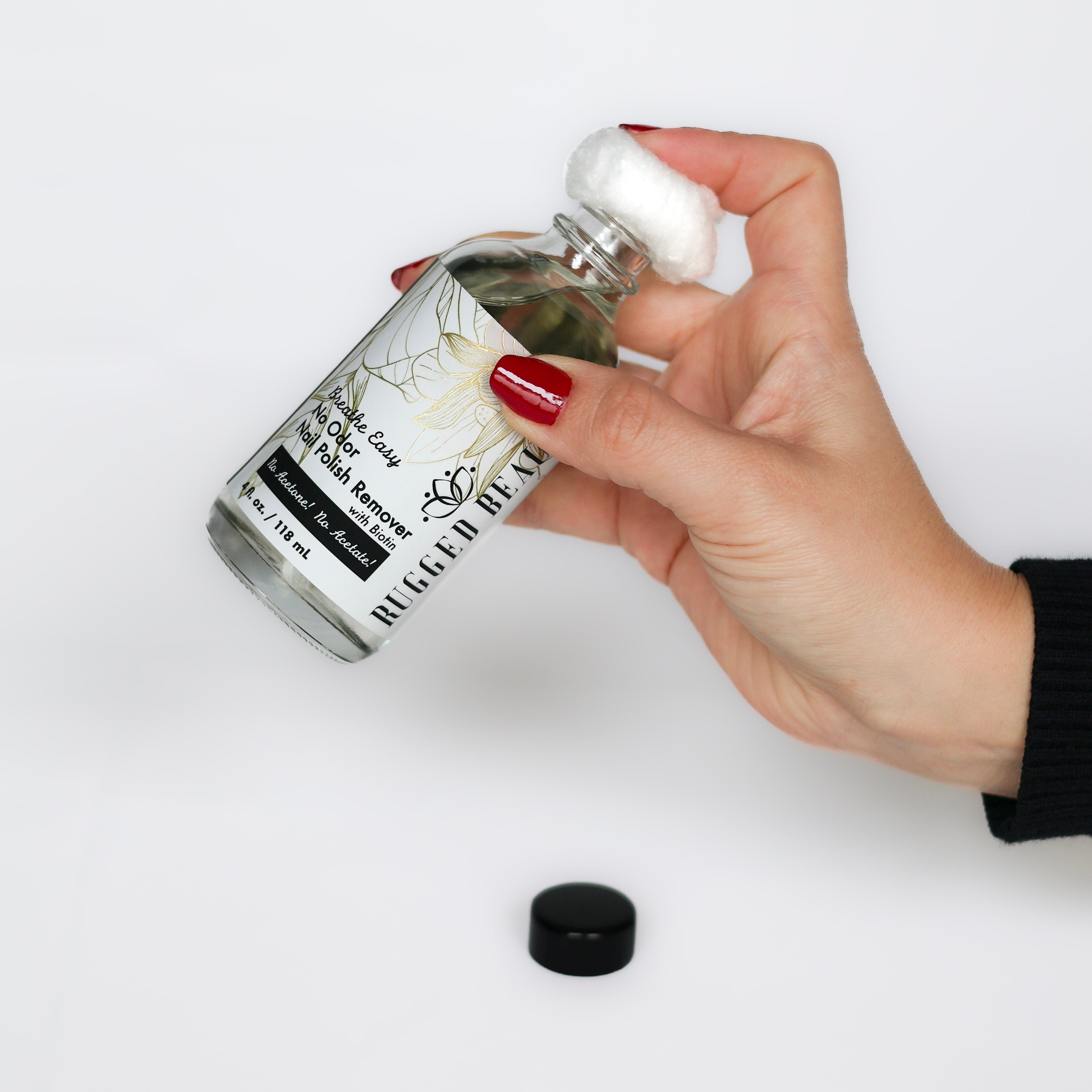 Hand holding a clear glass bottle with a white cap against a white background
