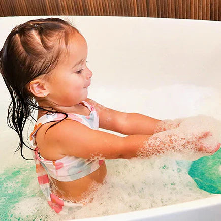 Child playing in a bathtub filled with bubbles and water.