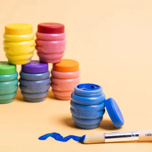 Colorful containers with lids and a blue marker on a beige background