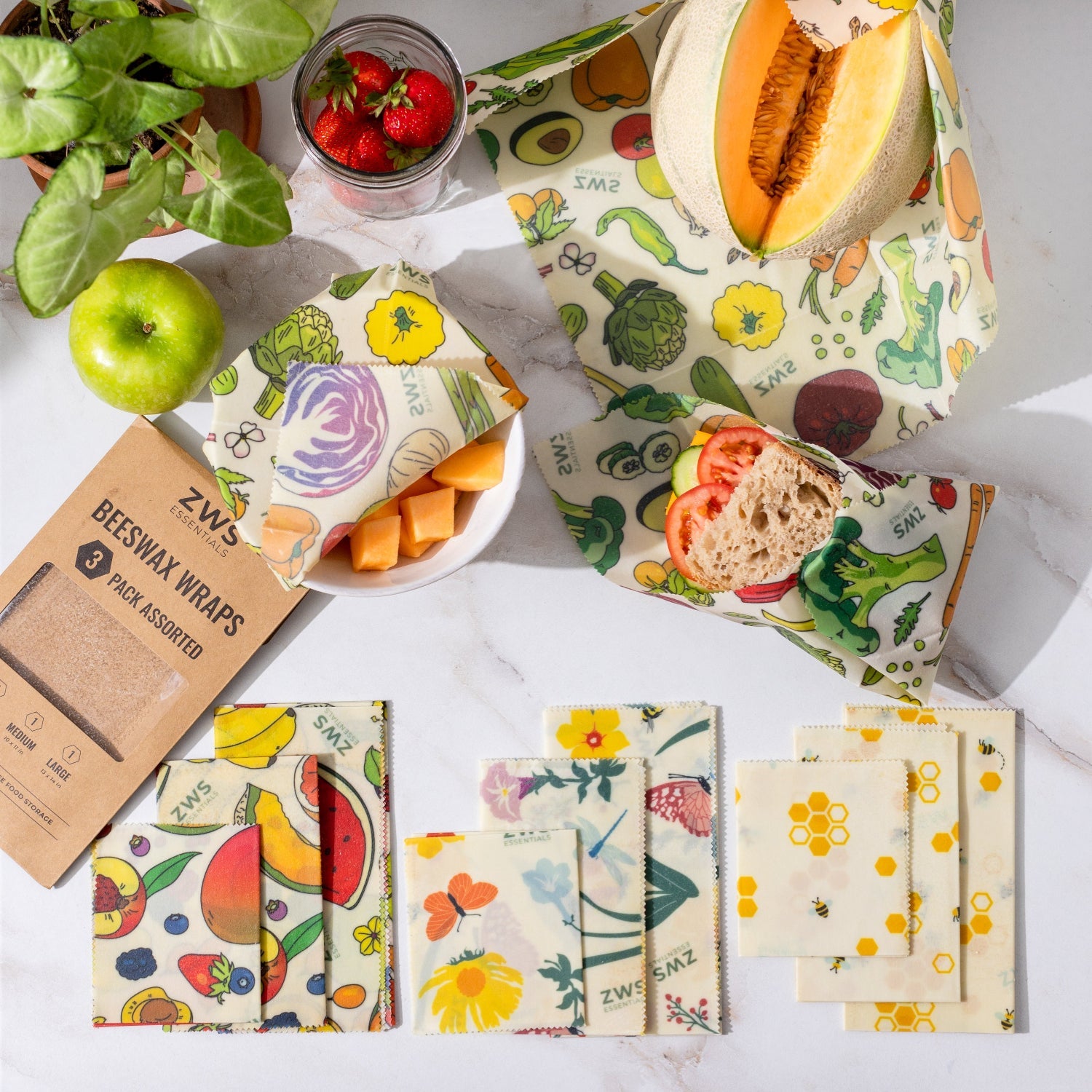 Assorted beeswax wraps with fruits and vegetables on a white surface